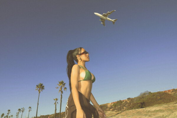 woman walking on the road while a plane flies overhead